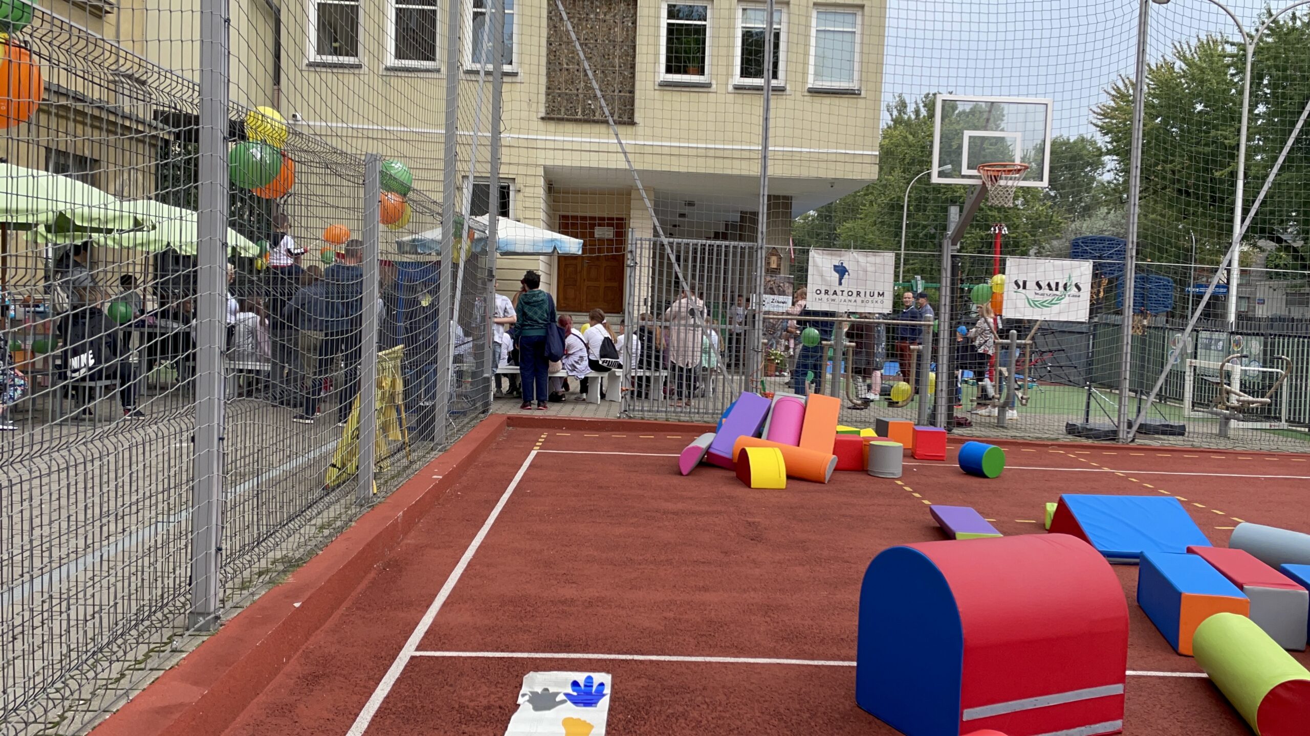 Festyn z torem z klocków. Kolorowy tor przeszkód z dużych klocków na boisku, balony i rodziny w oczekiwaniu na zabawę.